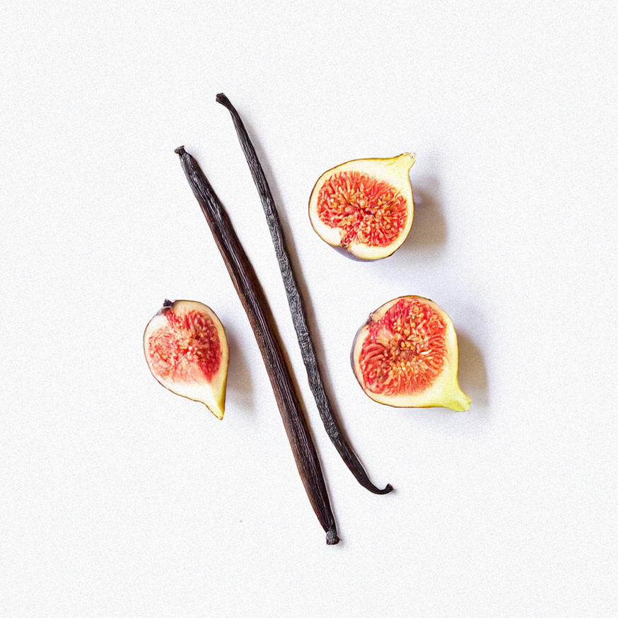 Two vanilla beans and four fig halves on a white background