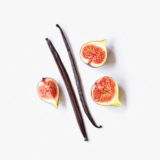 Two vanilla beans and four fig halves on a white background
